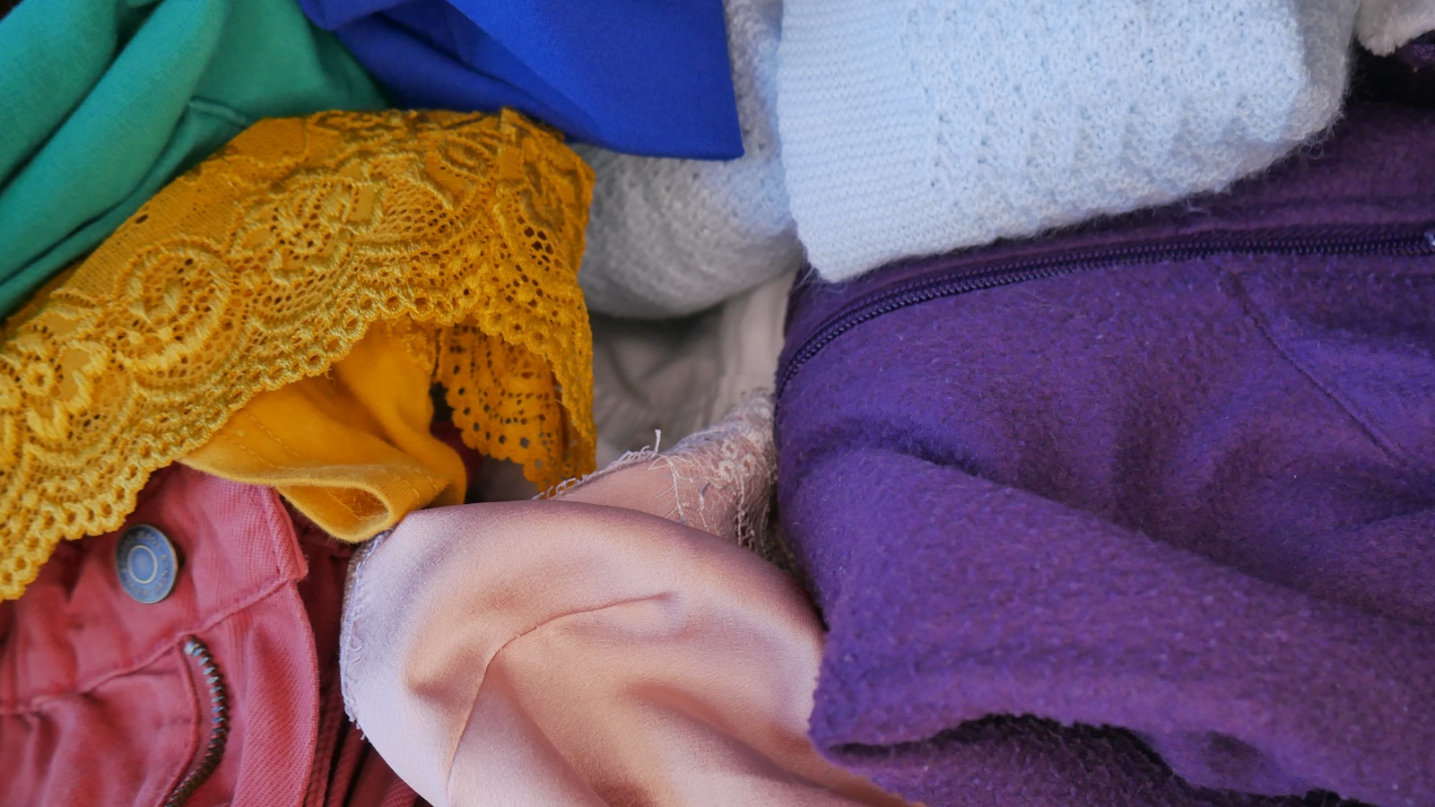 a pile of colorful clothing sitting on top of a bed