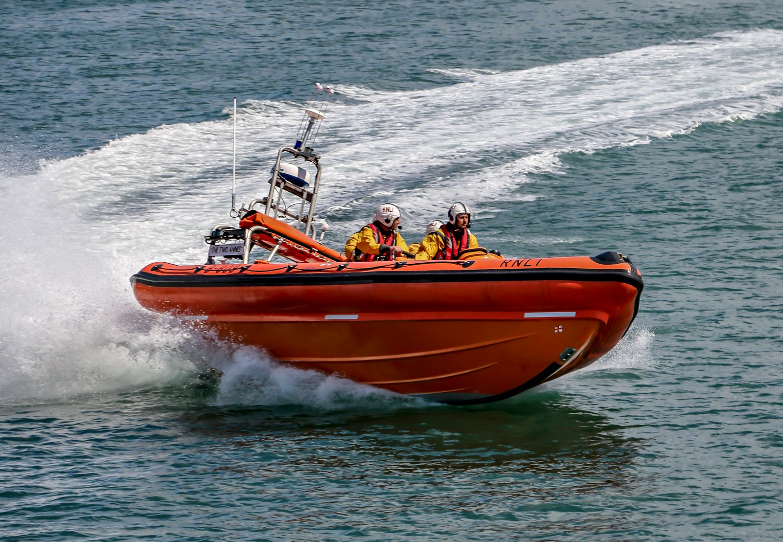 people riding orange and white boat on sea during daytime